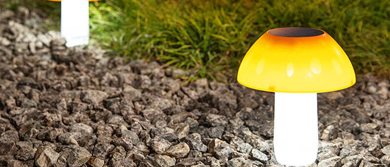 Solarleuchten im Garten – leuchtende Solar-Pilzleuchten an der Beetkante in der Dämmerung.
