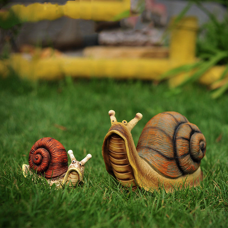 Deko Schnecke als wetterfeste Tier-Gartendeko im Blumenbeet zwischen Rosen und Lavendel