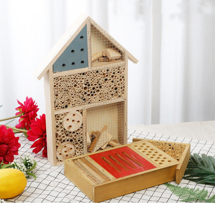 Insektenhotel in zwei Grössen auf Tischdecke mit roten Blumen – Bienenhotel gross und klein im Vergleich