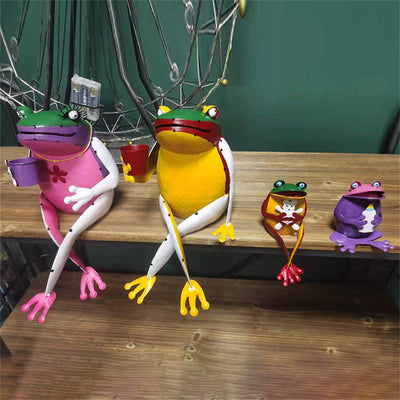 Gartenfigur Froschfamilie aus Metall: zwei grosse und zwei kleine Frösche in Pink, Gelb und Violett auf Holzbank