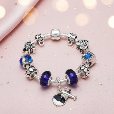 Charm-Armband Fernweh-Blau in Silber mit dunkelblauen Glasperlen, Flugzeug-Anhänger und Herz-Charms auf rosa Seide