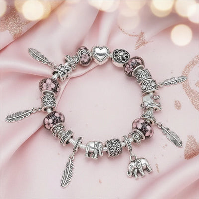 Charm-Armband Safari-Elefant mit rosa Glasperlen, Elefanten-Anhänger und silbernen Federn auf rosa Seidenstoff