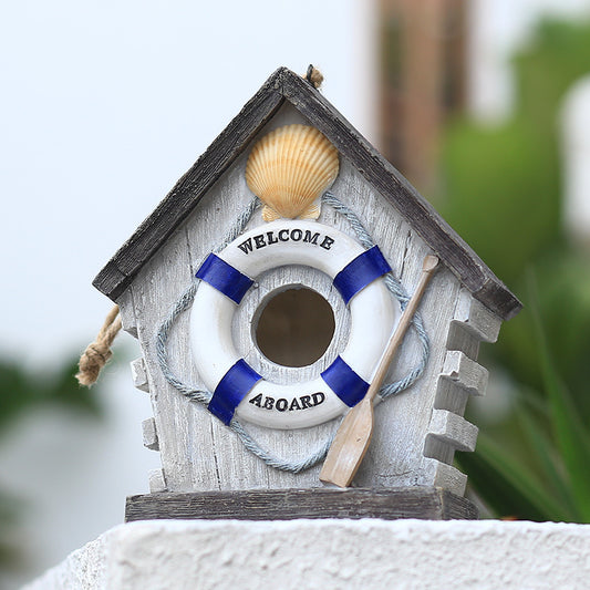 Hängendes Vogelhaus aus Kunstharz im maritimen Design mit Rettungsring und Muschel auf Steinsockel