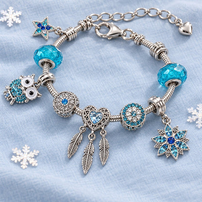 Türkises Armband auf hellblauem Stoff mit Eule, Herz-Traumfänger, Kristall-Schneeflocke und Stern