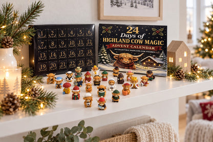 Highland-Kuh-Figuren als Weihnachtsdeko auf einem Wandregal mit Lichterkette und Tannenzweigen, daneben die Kalenderbox