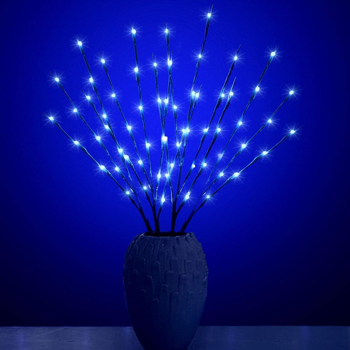 Dunkelbraune Leuchtzweige mit blauem Licht in einer dunklen Vase