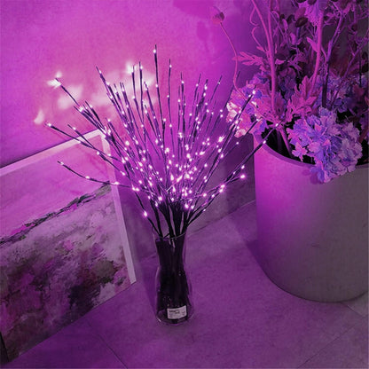 Leuchtzweige mit rosa Licht in einer Glasvase neben Blumen