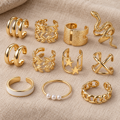 Goldene Ear Cuffs mit Blättern, Sternen und Schlange sowie Ringe mit weisser Emaille und drei Perlen auf Leinen
