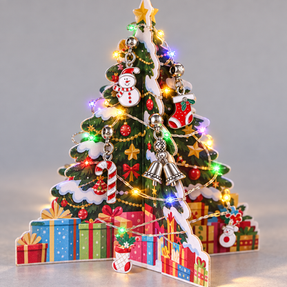 Aufgesteckter Kartonbaum mit bunten Lämpchen, daran Schneemann, Stiefel, Zuckerstange und Glocken